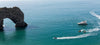 Boats near a large natural rock formation in the ocean